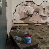 Il murales di un uomo senza braccia dedito all'autoerotismo: in primo piano gli attrezzi usati per disegnarlo